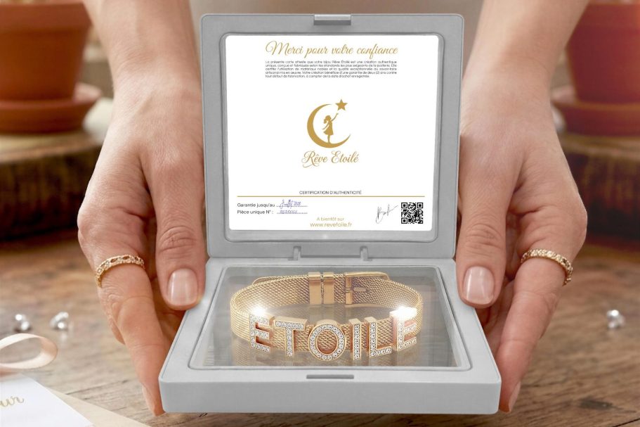Bracelet Collection Aura en Maille Milanaise Rêve Etoilé Coffret cadeau Rêve Étoilé ouvert présentant un bracelet personnalisé en maille milanaise dorée avec des lettres coulissantes en strass, ten